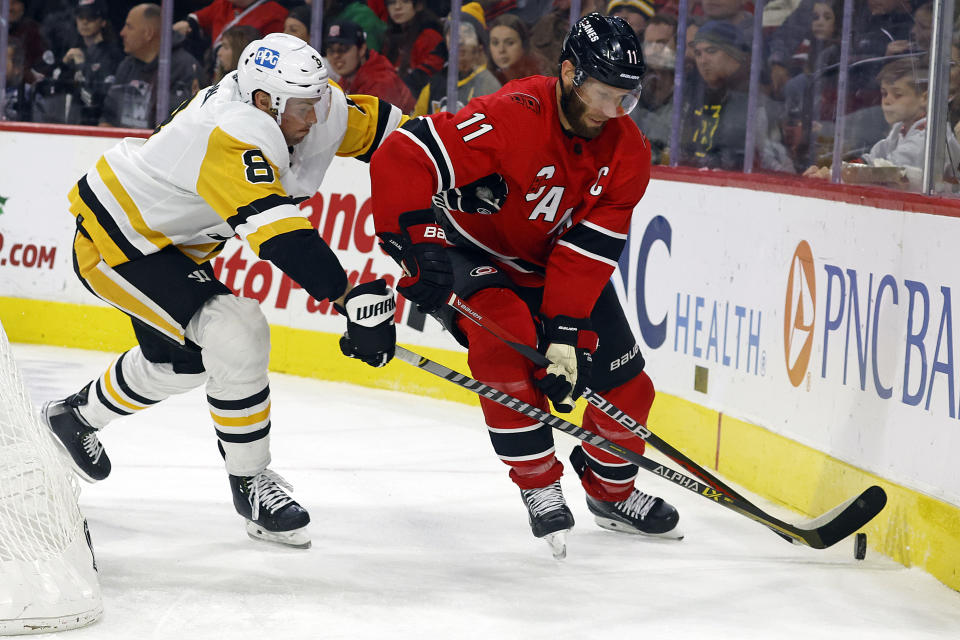 Carolina Hurricanes' Jordan Staal (11) protects the puck from Pittsburgh Penguins' Brian Dumoulin (8) during the second period of an NHL hockey game in Raleigh, N.C., Sunday, Dec. 18, 2022. (AP Photo/Karl B DeBlaker)