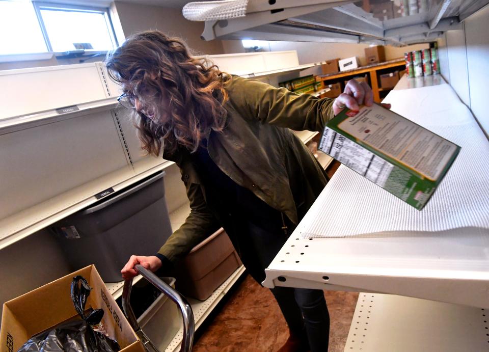 Allison Davis, an employee at Love & Care Ministries, grabs the last box of pasta from a shelf in the organization's food pantry as she makes boxes of food for families Nov. 16.