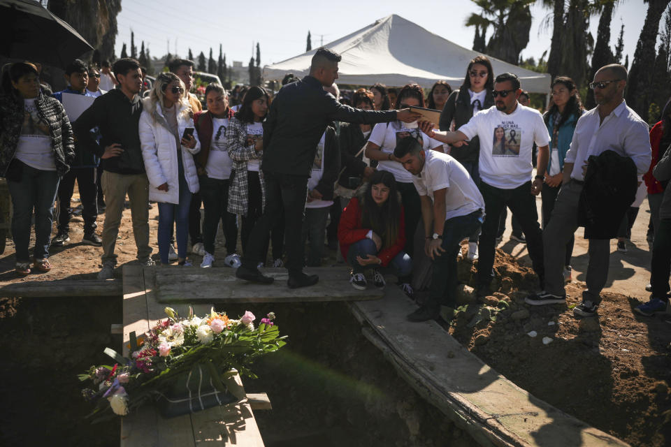 Juan, who has been arrested in connection with the disappearance and murder of Marbella Valdez, second from right, hands a portrait of the slain woman to her ex-boyfriend Jairo Solano, as her sister Brenda kneels below, and step-father William H. Hessik stands far right, during Valdez's burial at a cemetery in Tijuana, Mexico, Friday, Feb. 14, 2020. Juan, who sent her gifts and brought food for her friends, demanded police solve her case after the 20-year-old law student's body, beaten, bound and strangled was found at a Tijuana garbage dump. Juan has insisted on his innocence. (AP Photo/Emilio Espejel)