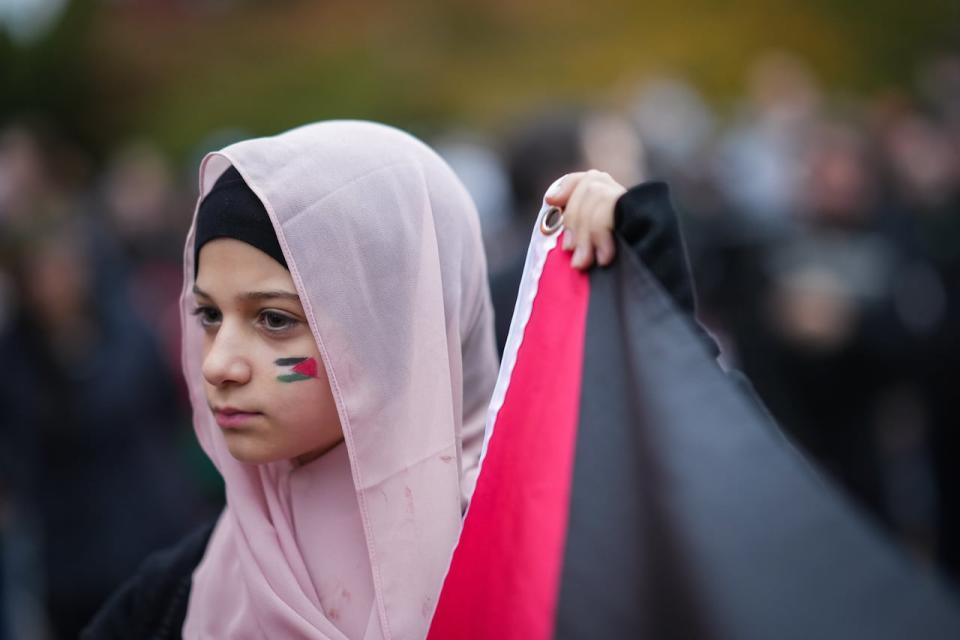 A young girl helps hold a Palestinian flag during a demonstration in support of Palestine in Vancouver on Thursday, October 19, 2023.
