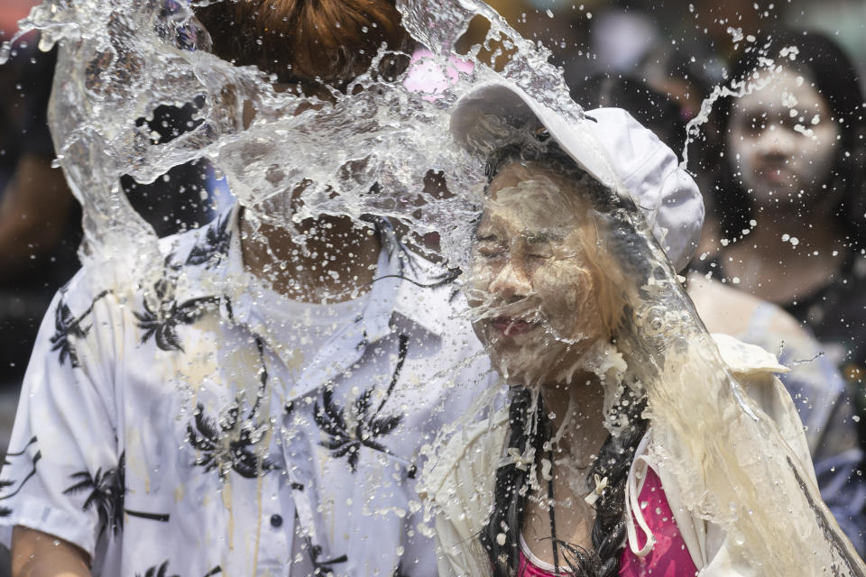 A couple react as a bucket of water is splashed on them during the Songkran water festival to celebrate the Thai New Year in Prachinburi Province, Thailand, Saturday, April 13, 2024. It's the time of year when many Southeast Asian countries hold nationwide water festivals to beat the seasonal heat, as celebrants splash friends, family and strangers alike in often raucous celebration to mark the traditional Theravada Buddhist New Year. (AP Photo/Wason Wanichakorn)