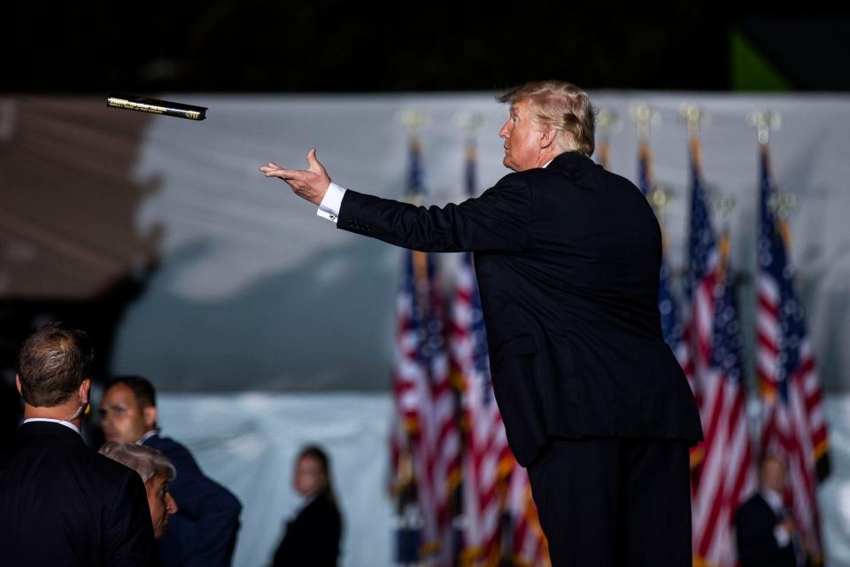 Former President Donald Trump, tosses a just-autographed book back into the crowd, on Saturday, Oct. 9, 2021, in Des Moines, Iowa. 