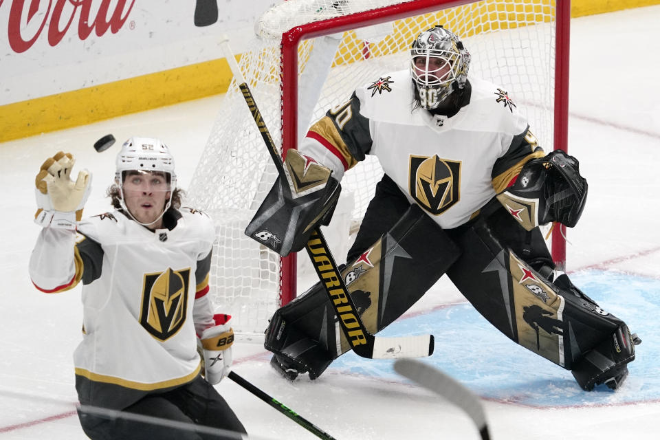 Vegas Golden Knights defenseman Dylan Coghlan, left knocks the puck out of the air as goaltender Robin Lehner watches during the third period of an NHL hockey game against the Los Angeles Kings Monday, April 12, 2021, in Los Angeles. (AP Photo/Mark J. Terrill)