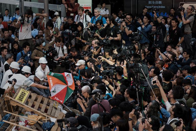 The media watch as bailiffs remove barricades set up by pro-democracy protesters in the Mongkok district of Hong Kong on November 25, 2014