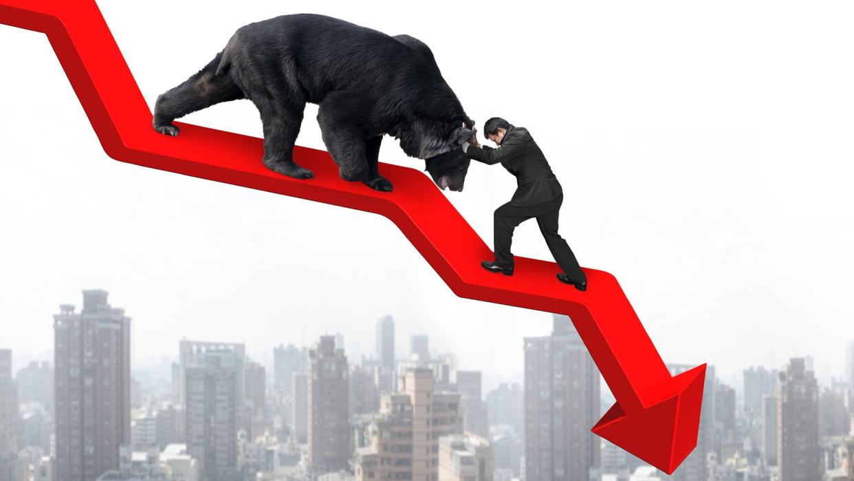 Businessman against black bear on red arrow downward trend line with sky cityscape background.