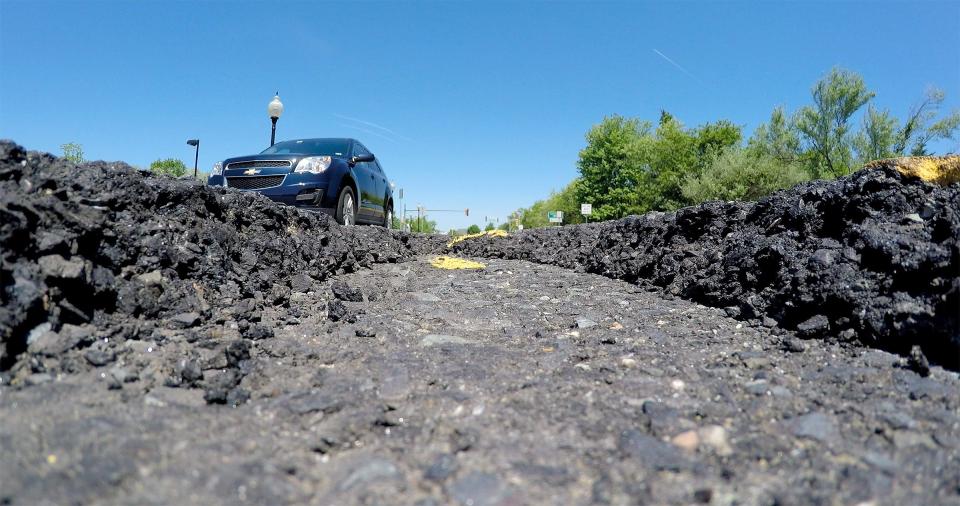 A car rolls past a a pothole outside Brick House Tavern on Premium Outlet Boulevard in Neptune Township Thursday, May 24, 2018.  