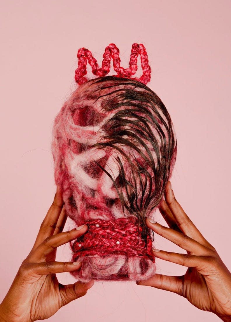 Hand Model Niani Simeone holds aloft Mia Crews' sculpture 'Dear, Black Women Keep Your Crown.'