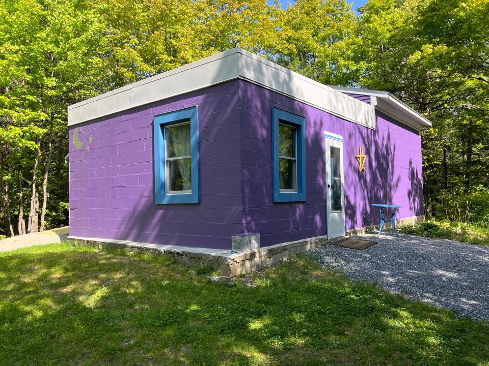 A planetarium in the woods in Williston that once was an observatory for the Vermont Astronomical Society, as seen on May 18, 2023. The Planetarium Lady, Carrie Cruz, kept the cornerstone with 1982 engraved on it, still in white and can be seen in the lower corner in the foreground, and an inscription over the door. She livened up the outside of the cinder block structure with colors, a moon and stars painting (at left) and a star decoration. During her renovation starting in 2020, she took down most of a wall, added windows, and replaced the retractable roof.