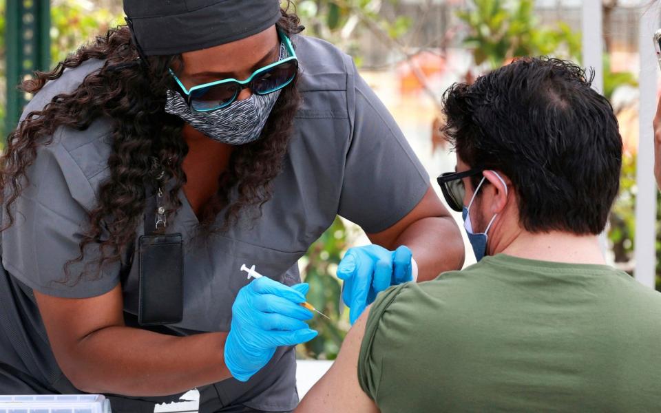 n this June 17, 2021, file photo, an Orange County resident receives the COVID-19 vaccine at the Florida Division of Emergency Management mobile vaccination site at Camping World Stadium in Orlando, Fla. COVID-19 deaths in the U.S. have dipped below 300 a day for the first time since the early days of the disaster in March 2020, while the number of Americans fully vaccinated has reached about 150 million.