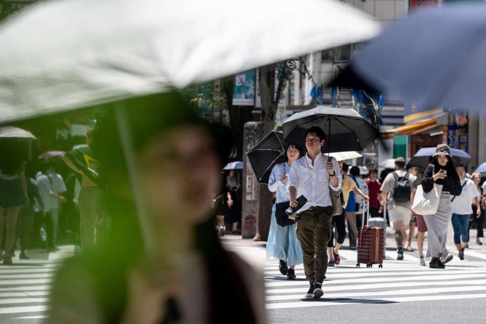 PHOTO: Men and women use umbrellas and parasols to seek relief from the heat while crossing a street in Tokyo, July 30, 2023. (Richard A. Brooks/AFP via Getty Images, FILE)