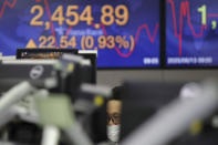 A currency trader watches computer monitors near a screen showing the Korea Composite Stock Price Index (KOSPI) at the foreign exchange dealing room in Seoul, South Korea, Thursday, Aug. 13, 2020. Asian shares were mostly higher on Thursday, cheered by the rally on Wall Street that's likely a boon for export-driven regional economies, even as investors worry about the coronavirus pandemic. (AP Photo/Lee Jin-man)