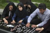 In this picture taken on Monday, April 28, 2014, Iranian woman Samereh Alinejad, left, her daughter Fatemeh and her husband Abdolghani Hosseinzadeh pray at the grave of the family's sons Amir Hossein and Abdollah in a cemetery in the city of Royan about 146 miles (235 kilometers) north of the capital Tehran, Iran. Amir Hossein was killed in a motorcycle crash and Abdollah was killed in a street brawl. Alinejad tells The Associated Press that she had felt she could never live with herself if the man who killed her son Abdollah were spared from execution. But in the last moment, she pardoned him in an act that has made her a hero in her hometown, where banners in the streets praise her family’s mercy. (AP Photo/Vahid Salemi)