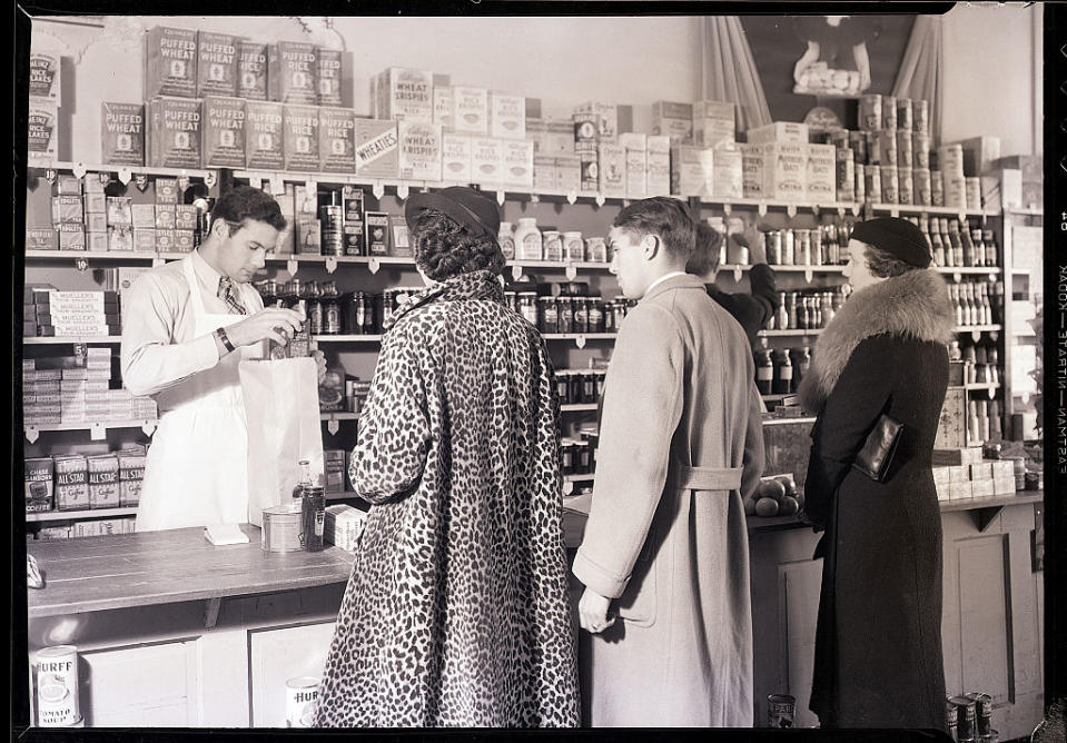 Vintage photo of a store clerk behind a counter assisting two customers