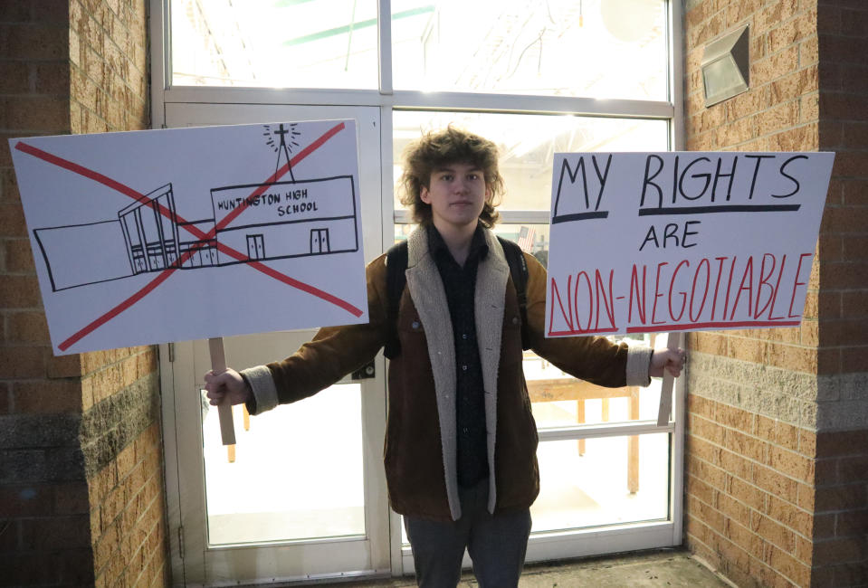 FILE - Huntington High School senior Max Nibert holds signs he plans to use during a walkout students are staging at Huntington High School in Huntington, W.Va. on Wednesday, Feb. 9, 2022. The protest follows an evangelistic Christian revival assembly at the school that some students were mandated by teachers to attend – a violation of students' civil rights, Nibert says. The West Virginia school district has passed a policy banning “proselytizing” or “denigrating” over faith as part of a lawsuit settlement after an evangelical preacher held a religious revival assembly during the school day in 2022 that some students were required to attend. (AP Photo/Leah M. Willingham, File)