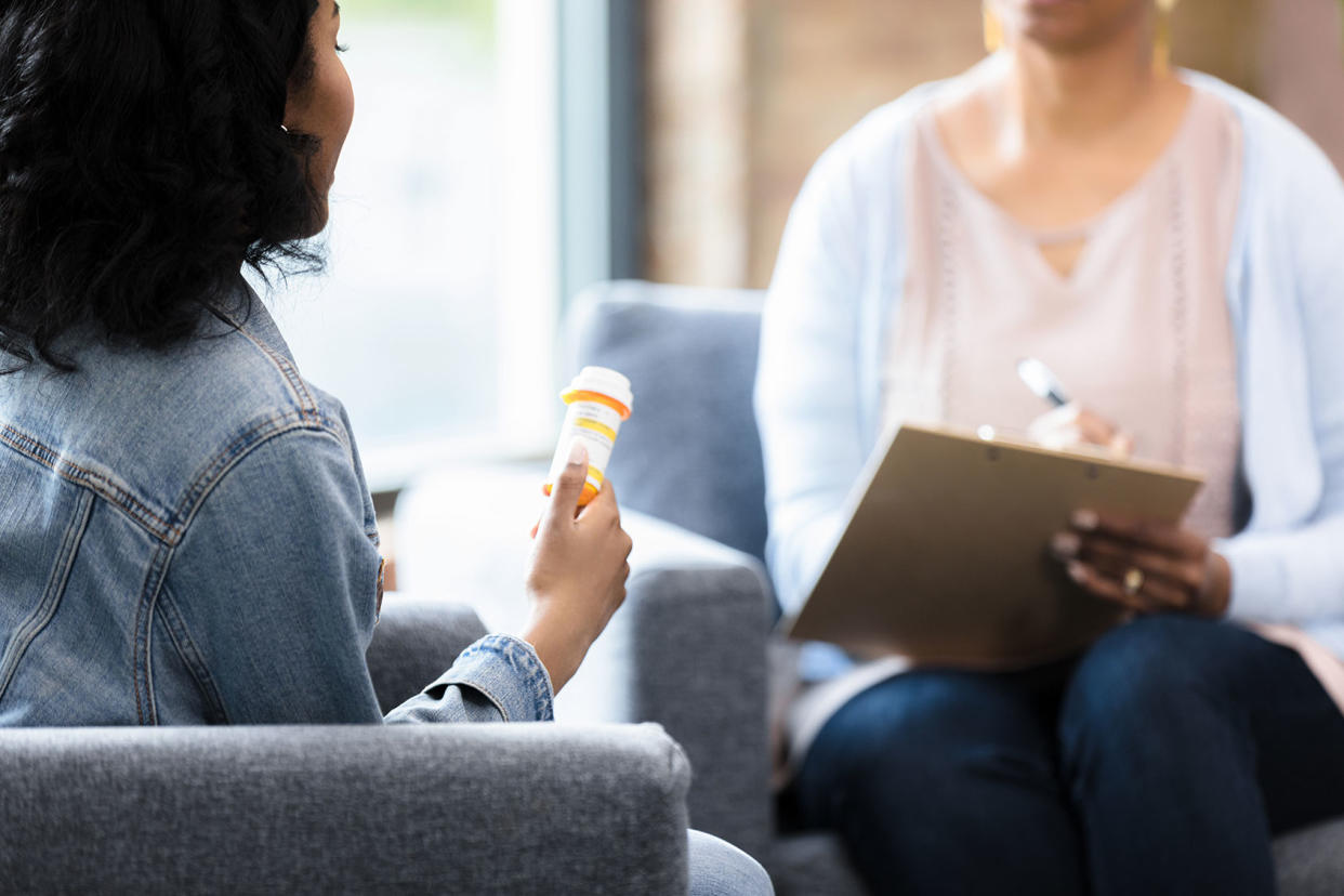 The young woman holds onto the prescription bottle while she listens to the doctor Getty Images/SDI Productions