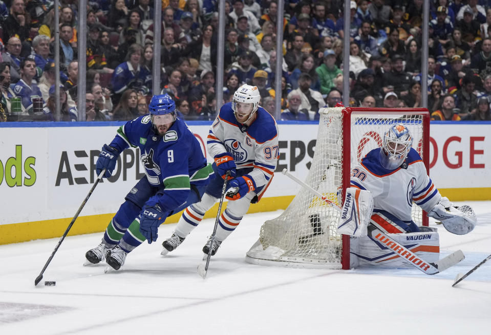 Vancouver Canucks' J.T. Miller (9) skates with the puck while being watched by Edmonton Oilers' Connor McDavid (97) and goalie Calvin Pickard (30) during the third period of Game 5 of an NHL hockey Stanley Cup second-round playoff series, Thursday, May 16, 2024, in Vancouver, British Columbia. (Darryl Dyck/The Canadian Press via AP)