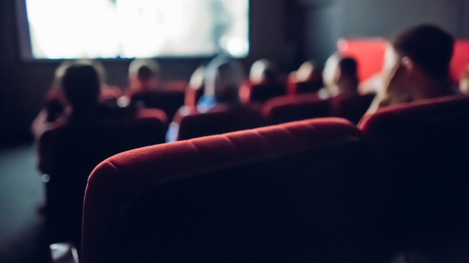 A blurred image of people watching a film in a movie theater