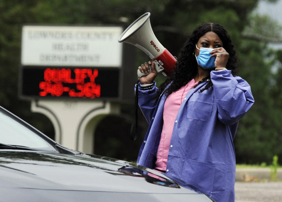 In this May 27, 2020, photo, health care worker Tonya Wilkes adjusts her mask while working at a Lowndes County coronavirus testing site in Hayneville, Ala. Experts say Lowndes County and nearby poor, mostly black counties in rural Alabama are now facing a “perfect storm” as infections tick up: a lack of access to medical care combined with poverty and the attendant health problems that can worsen the outcomes for those who become sick. (AP Photo/Jay Reeves)