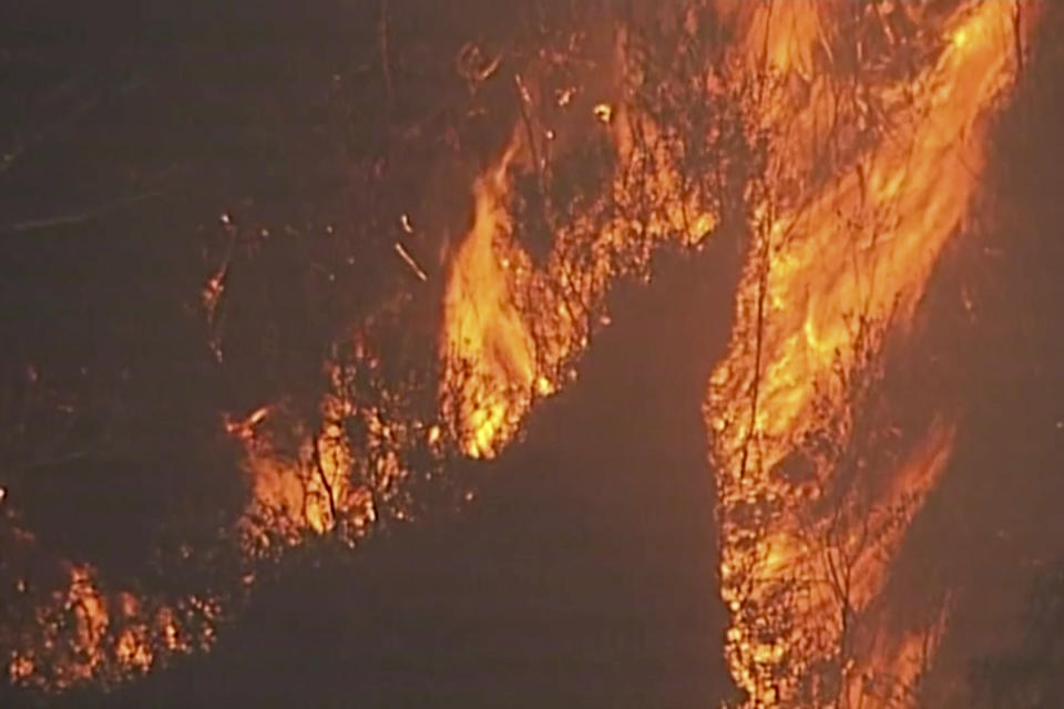 In this image made from video, fire and smoke rise from a bushfire at Blue Mountains, New South Wales state, Australia Sunday, Dec. 22, 2019. Australian Prime Minister Scott Morrison on Sunday apologized for taking a family vacation in Hawaii as deadly bushfires raged across several states, destroying homes and claiming the lives of two volunteer firefighters.(Australian Broadcasting Corporation via AP)