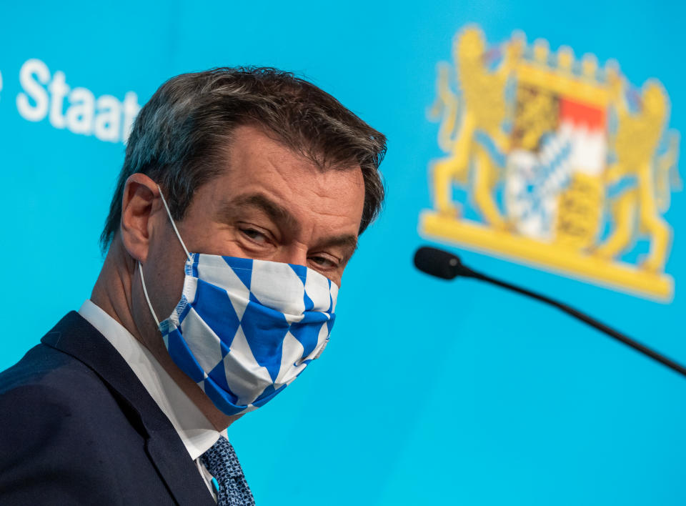 16 June 2020, Bavaria, Munich: Markus Söder (CSU), Prime Minister of Bavaria, puts on his mouth and nose protection mask in a white-blue diamond design after a press conference that took place after the Bavarian cabinet meeting. Photo: Peter Kneffel/dpa (Photo by Peter Kneffel/picture alliance via Getty Images)