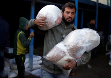 A Palestinian man carries food supplies at a United Nations food distribution center in Al-Shati refugee camp in Gaza City January 15, 2018. Picture taken January 15, 2018. REUTERS/Mohammed Salem