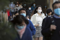 Commuters wearing face masks to help curb the spread of the coronavirus walk out from a subway station during the morning rush hour in Beijing, Tuesday, Oct. 27, 2020. (AP Photo/Andy Wong)