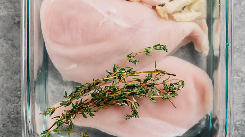 raw chicken breasts brining with herbs