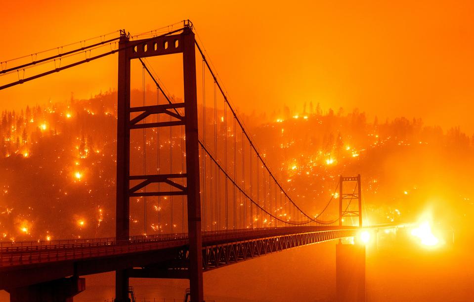 In this image taken with a slow shutter speed, embers light up a hillside behind the Bidwell Bar Bridge as the Bear Fire burns in Oroville, Calif., on Sept. 9, 2020. The blaze, part of the lightning-sparked North Complex, expanded at a critical rate of spread as winds buffeted the region.