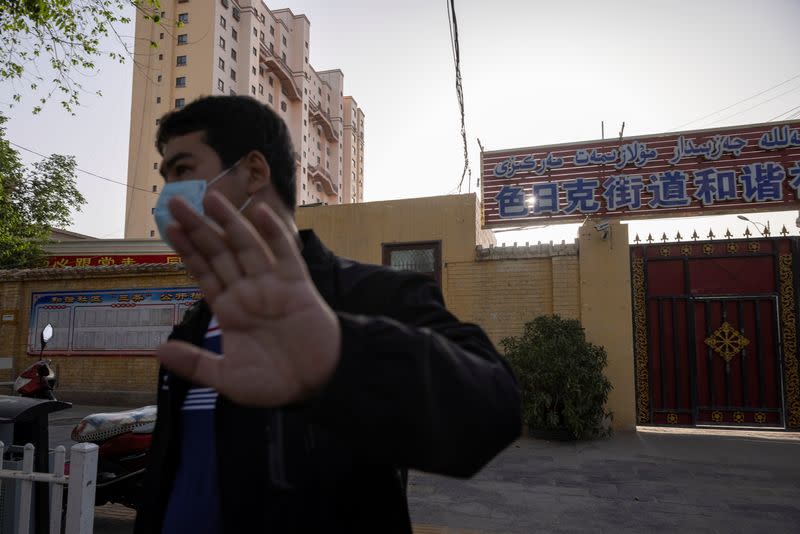 An unidentified man attempts to prevent the photographer from taking pictures outside the site of the Jiaman Mosque in Qira