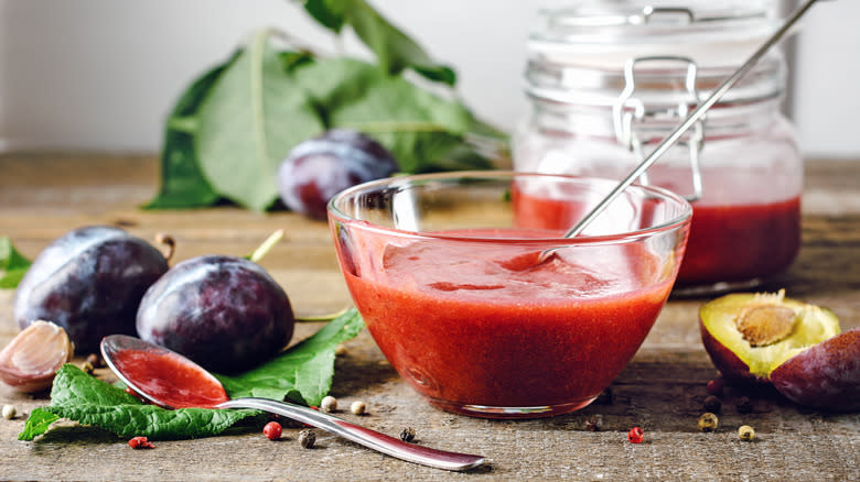 homemade plum sauce in bowl next to plums