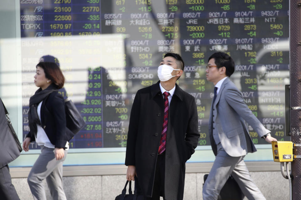In this Thursday, Nov. 21, 2019, photo, people walk in front of an electronic stock board of a securities firm in Tokyo. Stocks logged modest gains Friday, Nov. 22, 2019, in Asia after a lackluster overnight session on Wall Street ended with the market’s third straight drop. (AP Photo/Koji Sasahara)