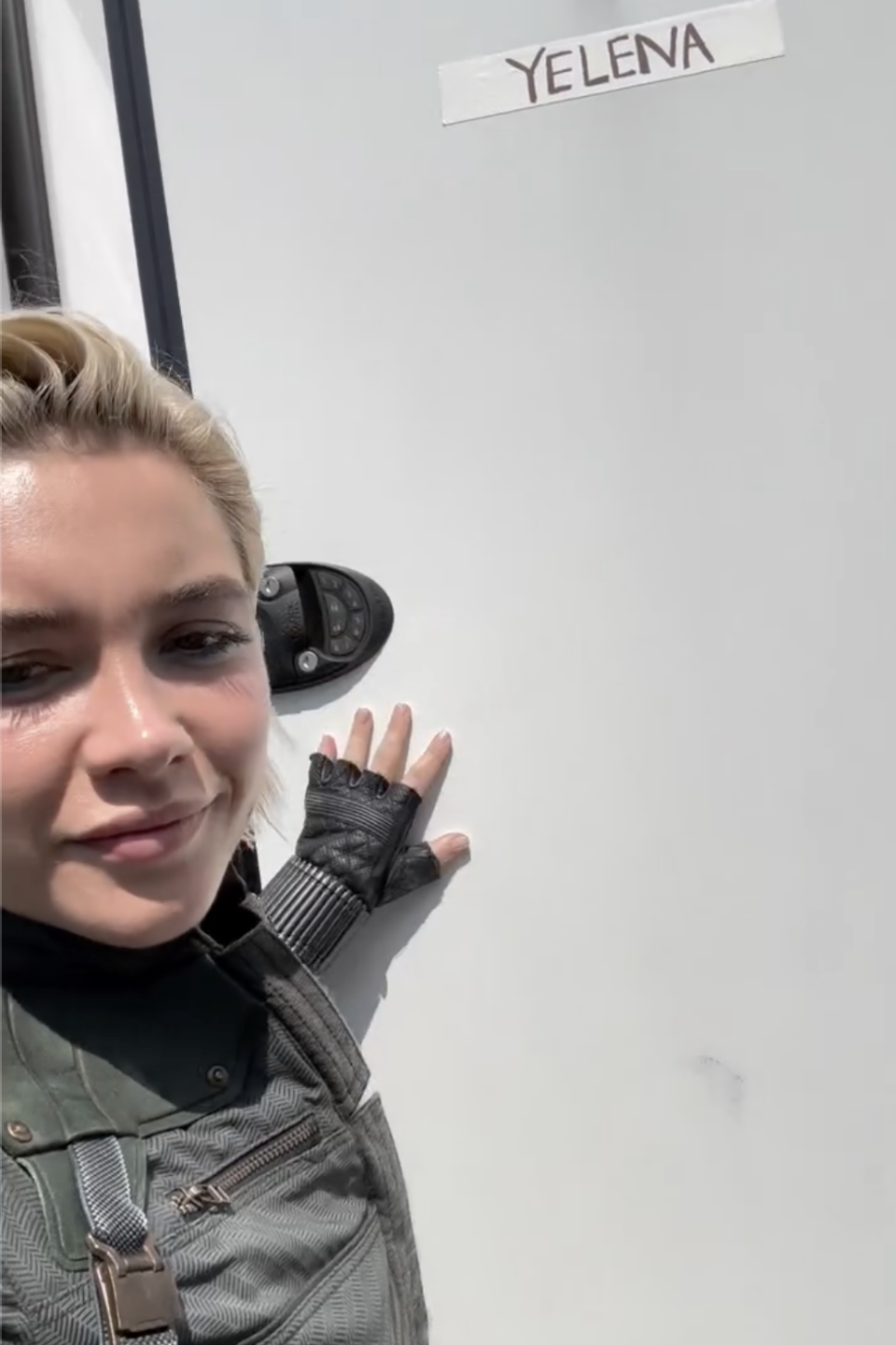 Florence Pugh posing next to a trailer door labeled 