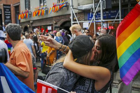 Women kiss each other as people celebrate outside the Stonewall Inn in the Greenwich Village neighborhood of New York June 26, 2015. REUTERS/Eduardo Munoz