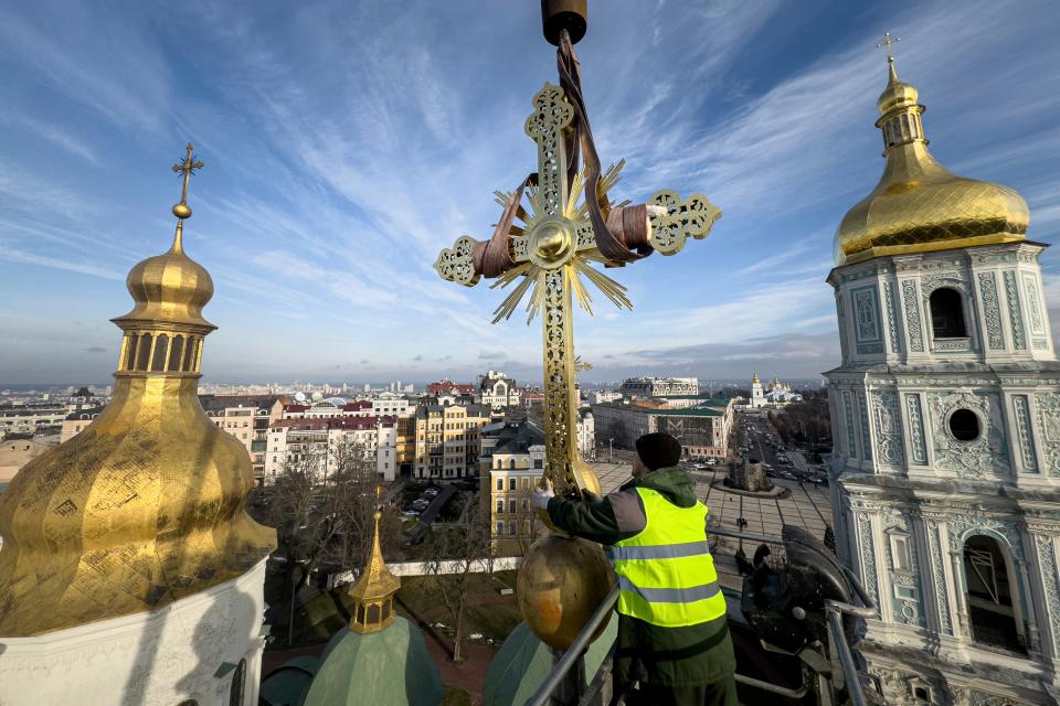 Ihor Kuzmenko, altitude worker installs a restored cross on a dome of Saint Sophia Cathedral in Kyiv (AP)