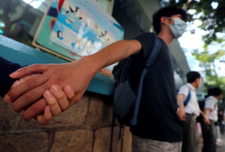 Secondary school students hold hands as they form a human chain demonstrating against what they say is police brutality against protesters, after clashes at Wan Chai district in Hong Kong