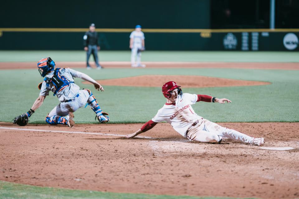 Arkansas baseball's Ty Wilmsmeyer slides safely into home off a sacrifcie fly by Jared Sprague-Lott for the game-winning run in a 2-1 victory over Florida Friday, April 26, 2024.