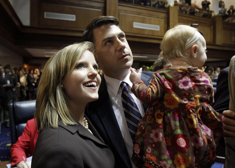 Indiana Republican Sen. Jim Banks, holds his daughter, Lillian, while his wife Amanda Banks looks up after taking the oath of office during organization day at the Statehouse in Indianapolis, Tuesday, Nov. 16, 2010. (AP Photo/Darron Cummings)