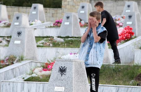 A boy prays at the grave of a relative, who was one of the forty-five ethnic Albanians killed by Serbian forces in January 1999, in the Recak village, Kosovo September 22, 2016. REUTERS/Hazir Reka
