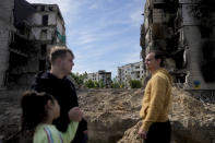 People stand in front of a building damaged by shelling in Borodyanka, on the outskirts of Kyiv, Ukraine, Wednesday, May 25, 2022. (AP Photo/Natacha Pisarenko)