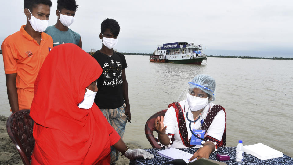 In this photo provided by Bidyanondo Foundation, a doctor examines a patient after arriving at Banishanta village near Mongla seaport in southwestern region of Bangladesh, on Sept. 1, 2020. A Bangladeshi charity has set up a floating hospital turning a small tourist boat into a healthcare facility to provide services to thousands of people affected by this year's devastating floods that marooned millions. (Bidyanondo Foundation via AP)