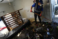 A contractor cleans personal items from a ground-floor river-front apartment which was flooded during the passage of Hurricane Ian, at the Riverwalk housing complex in Fort Myers, Fla., Wednesday, Oct. 5, 2022. According to a neighbor who aided in their rescue and preferred not to be identified, the family with two young children who lived there was trapped inside after flooding from the river burst down their front door, tearing the jam from the wall, and flooded the apartment to waist-height. Neighbors helped them to safety in a nearby second-story unit.(AP Photo/Rebecca Blackwell)