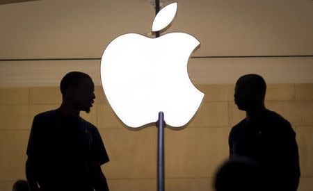 Customers stand beneath an Apple logo at the Apple store in Grand Central station in New York City, July 21, 2015. REUTERS/Mike Segar