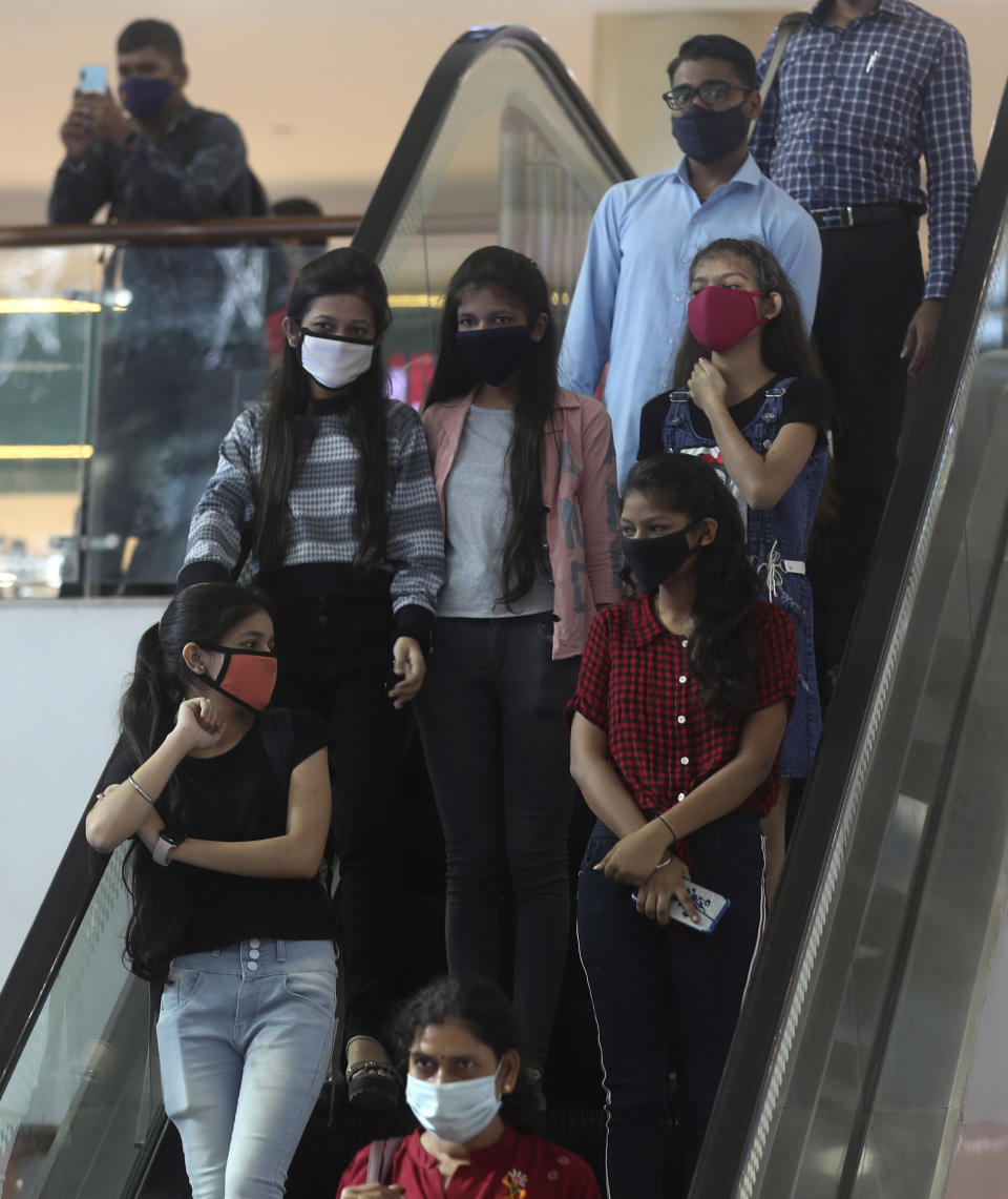 People wearing face masks use an escalator in a mall in Mumbai, India, Friday, Dec. 18, 2020. (AP Photo/Rafiq Maqbool)