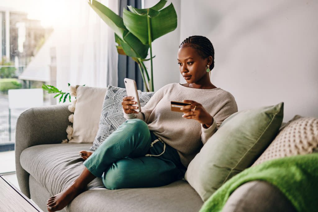 A woman looks at her phone and credit card. 