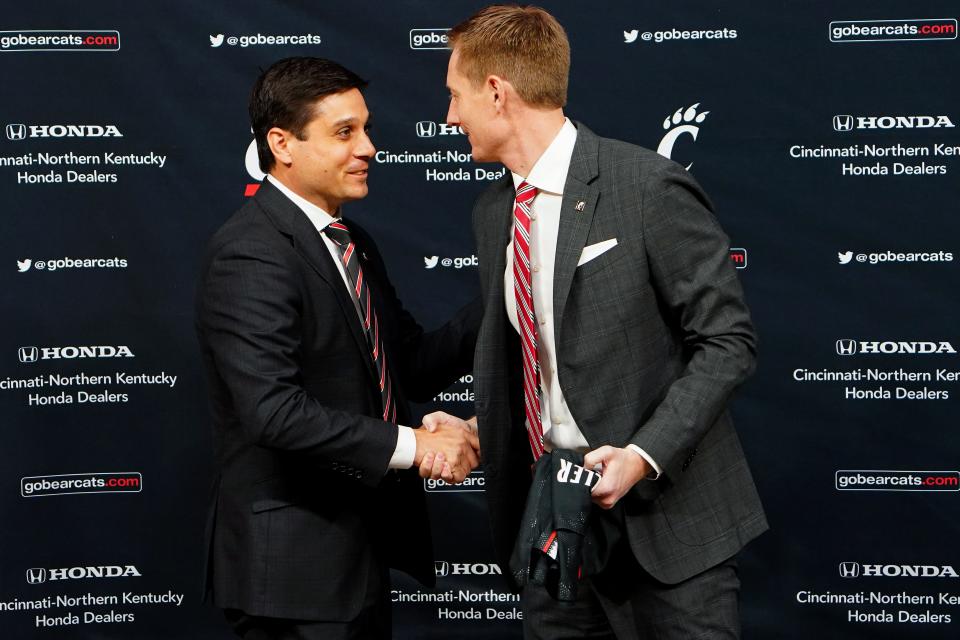 Wes Miller, left, shakes hands with University of Cincinnati Director of Athletics John Cunningham as he was formally introduced as the new University of Cincinnati men's basketball coach, Friday, April 16, 2021, at Fifth Third Arena. The wife of the late Skip Prosser, Nancy, was on hand. Nancy is a UC emergency room nurse and knew Miller's father from her time at Wake Forest.