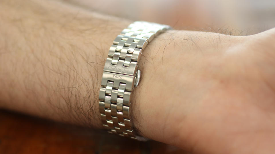 The Christopher Ward Consort bracelet in use on a C63 Sealander GMT, against a wooden background