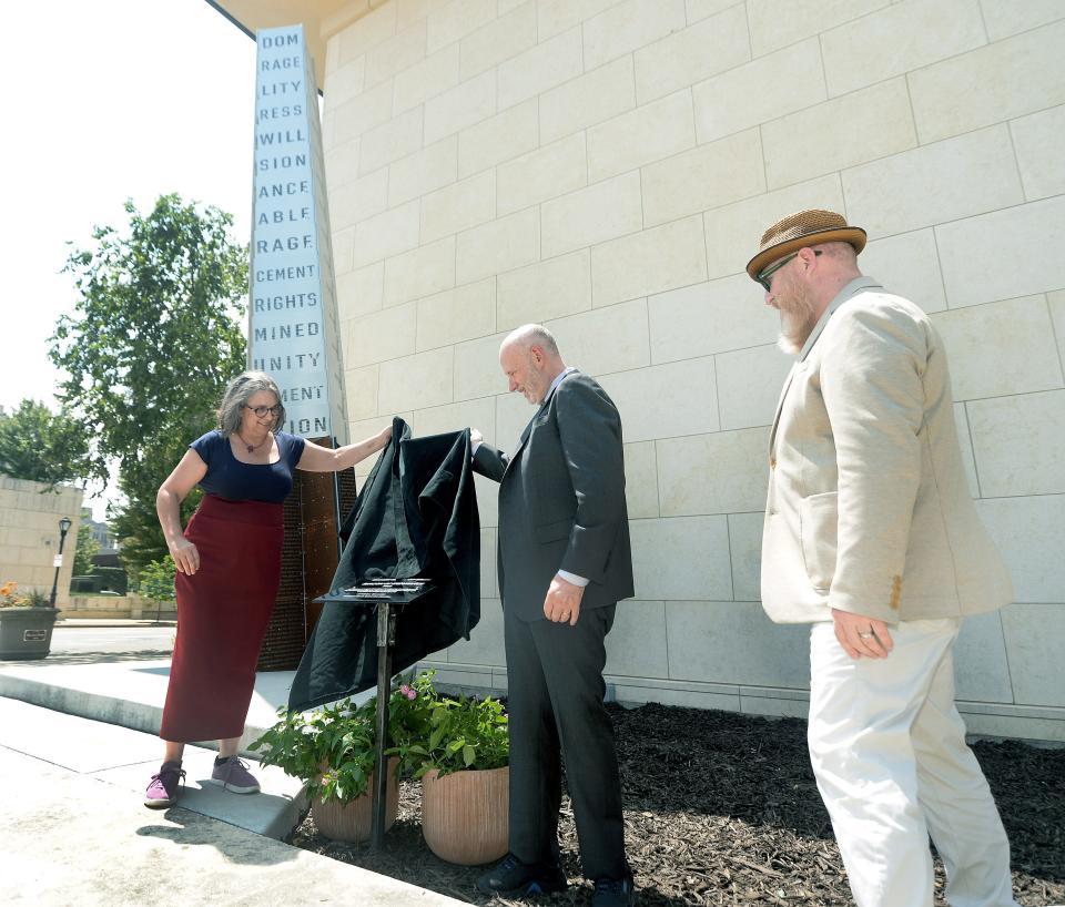 Art-in-Architecture Coordinator Linda Norbut Suits, left, and Chairman of the Board of the Abraham Lincoln Presidential Library & Museum Gary Johnson, center, unveil the plaque for the new sculpture "Beacon of Endurance" Wednesday July 19, 2023, located behind them, at the southeast corner of the museum. Also in the photo is Director of Exhibits and Shows Lance Tawzer.
