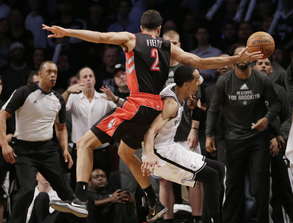 Toronto Raptors' Landry Fields, above, falls over Brooklyn Nets' Shaun Livingston, below as he chased a ball out of bounds during the second half of Game 3 of an NBA basketball first-round playoff series Friday, April 25, 2014, in New York. The Nets won 102-98. (AP Photo/Frank Franklin II)