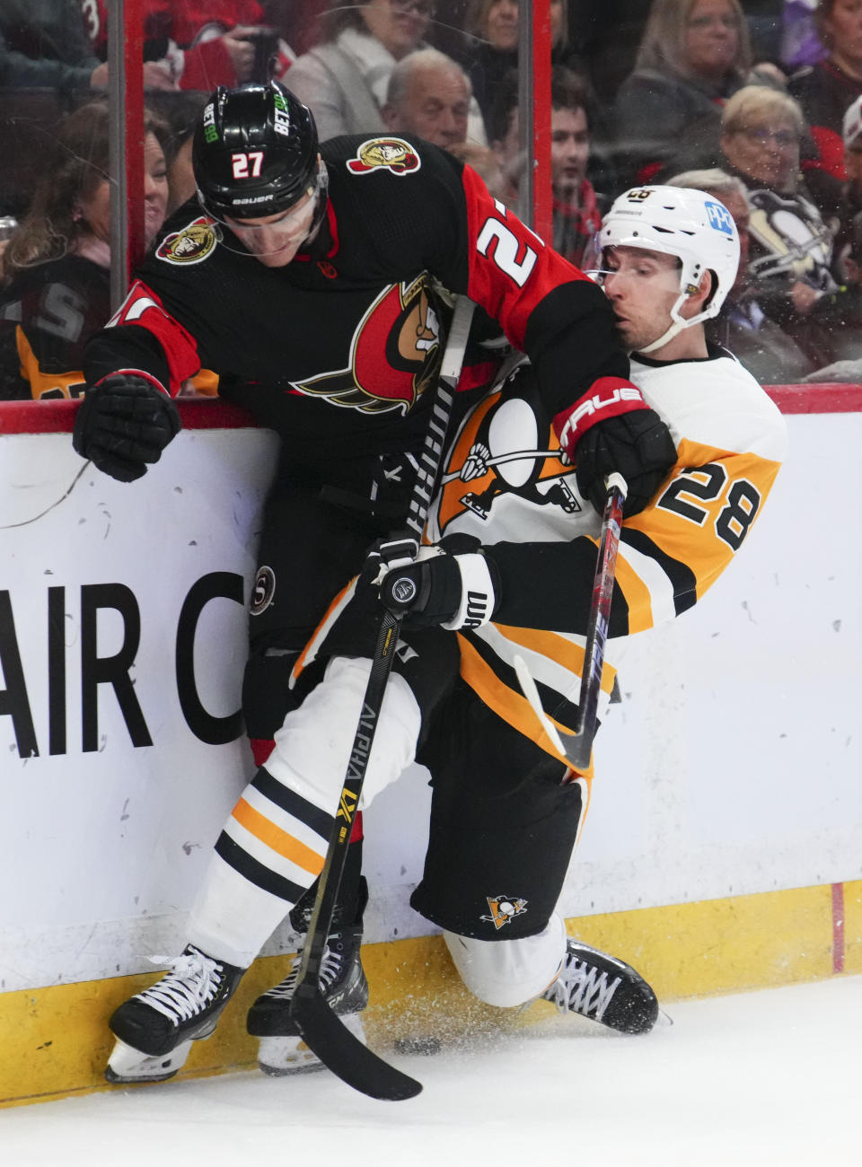 Ottawa Senators center Dylan Gambrell (27) and Pittsburgh Penguins defenseman Marcus Pettersson (28) battle along the boards during the second period of an NHL hockey game Wednesday, Jan. 18, 2023, in Ottawa, Ontario. (Sean Kilpatrick/The Canadian Press via AP)