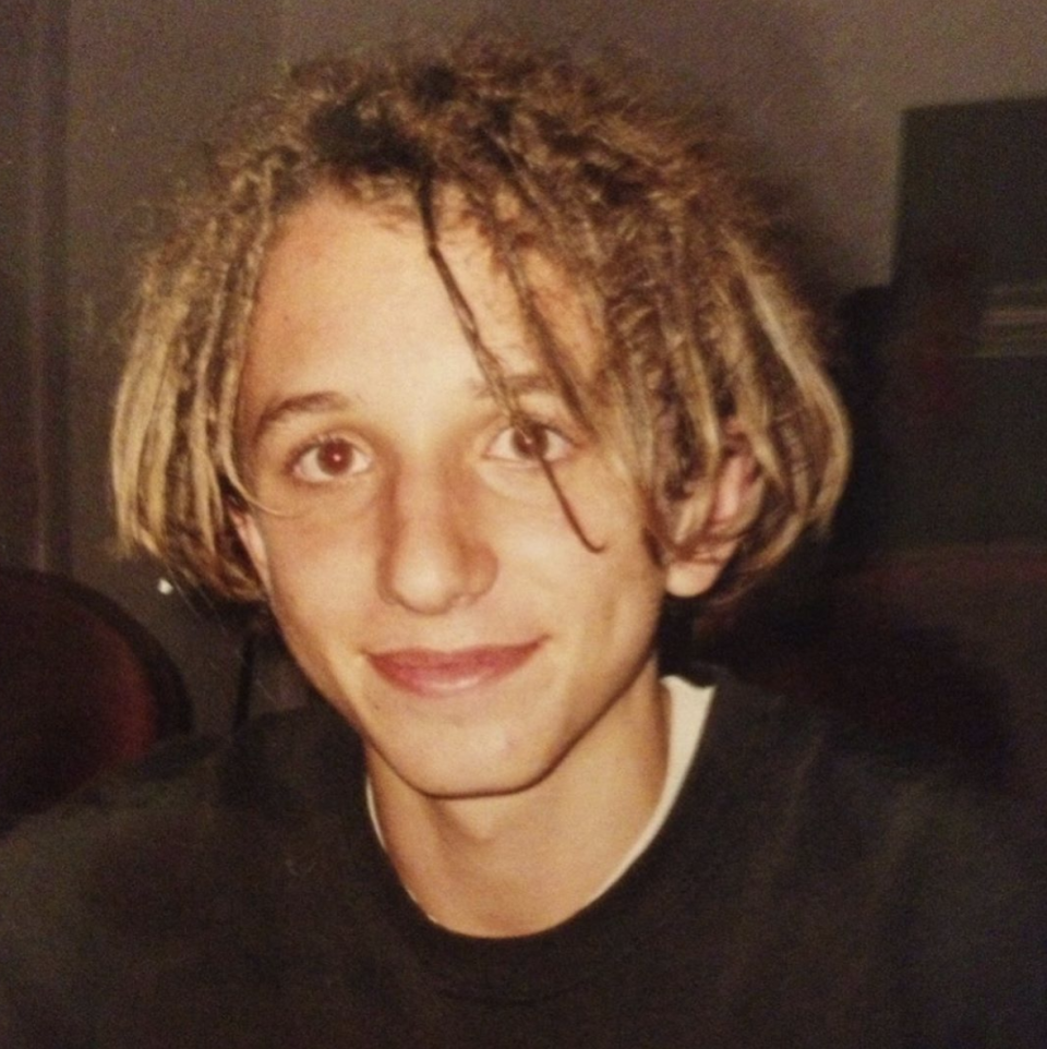 A teenaged Tommy Little wearing a black t-shirt and dreadlocked hair